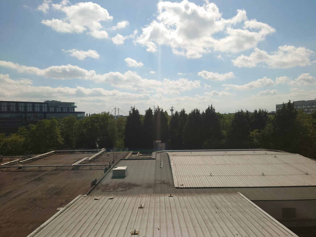 A photo from the 5th floor of the Hilton Birmingham Metropole at Birmingham NEC, overlooking part of the lake by the NEC towards Resort Word. The lower half of the view is obscured by the ground floor buildings of the hotel.