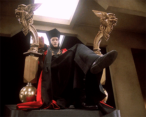 A GIF of Q in his 21st Century "post-atomic horror" Court Judge attire, flippantly gesturing with his hands as if to disregard some argument